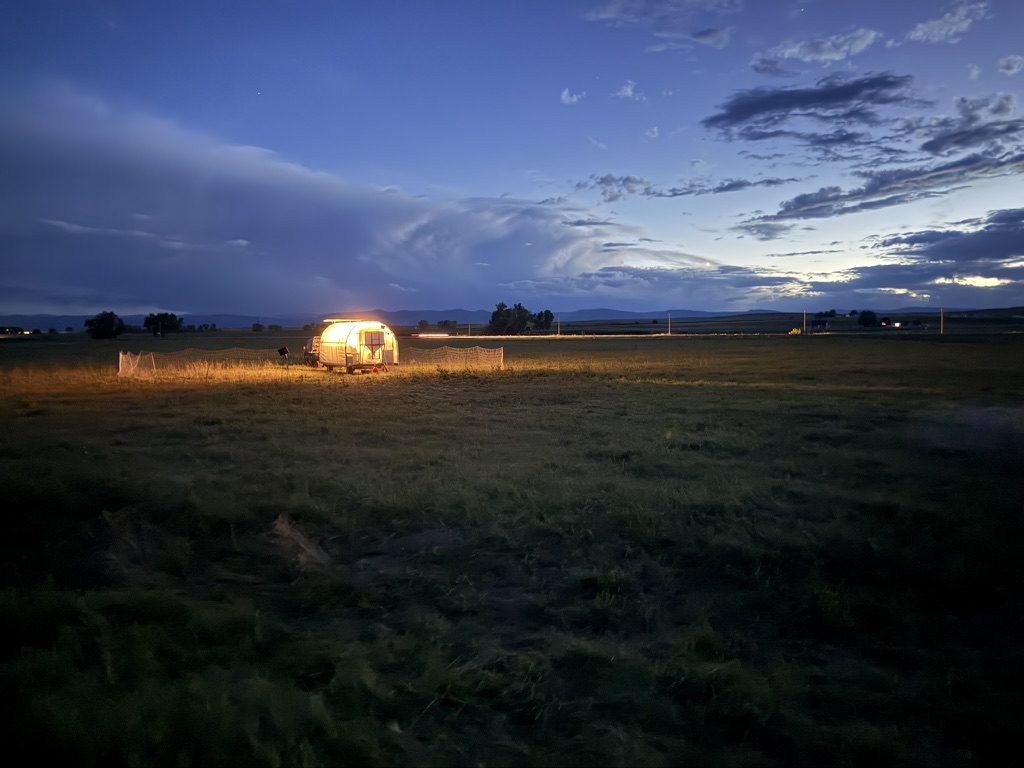 The chicken trailer lit up in a pasture at dusk