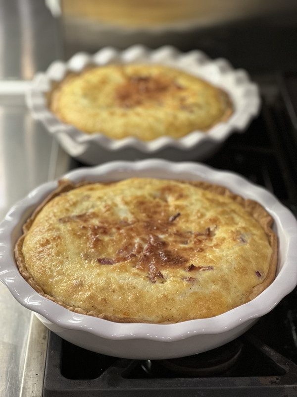 Two golden baked quiches in fluted dishes